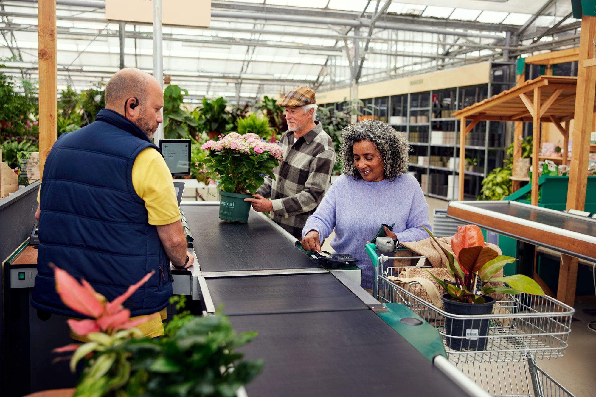 A customer at a counter in a garden center paying for plants by tapping her card on Adyen's M400 terminal.