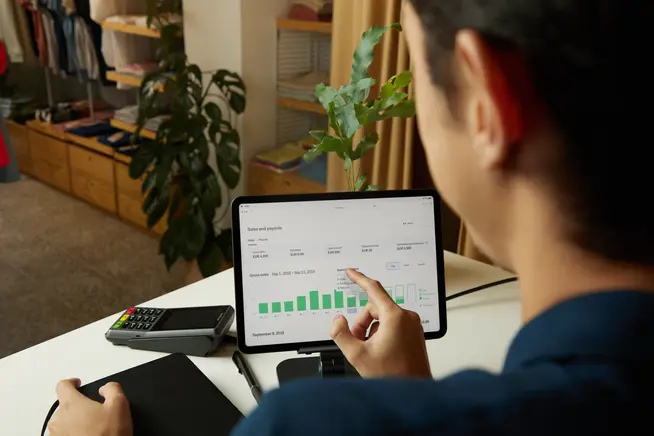 Persona que analiza las ventas y los pagos en una tableta con la interfaz de pago de Adyen.