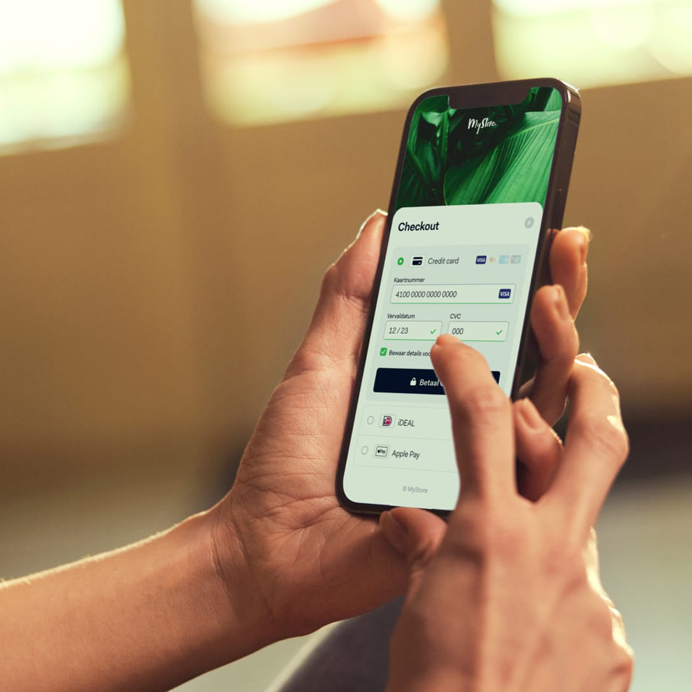 Primeiro plano de mãos usando um smartphone para concluir um pagamento na tela de pagamento Adyen