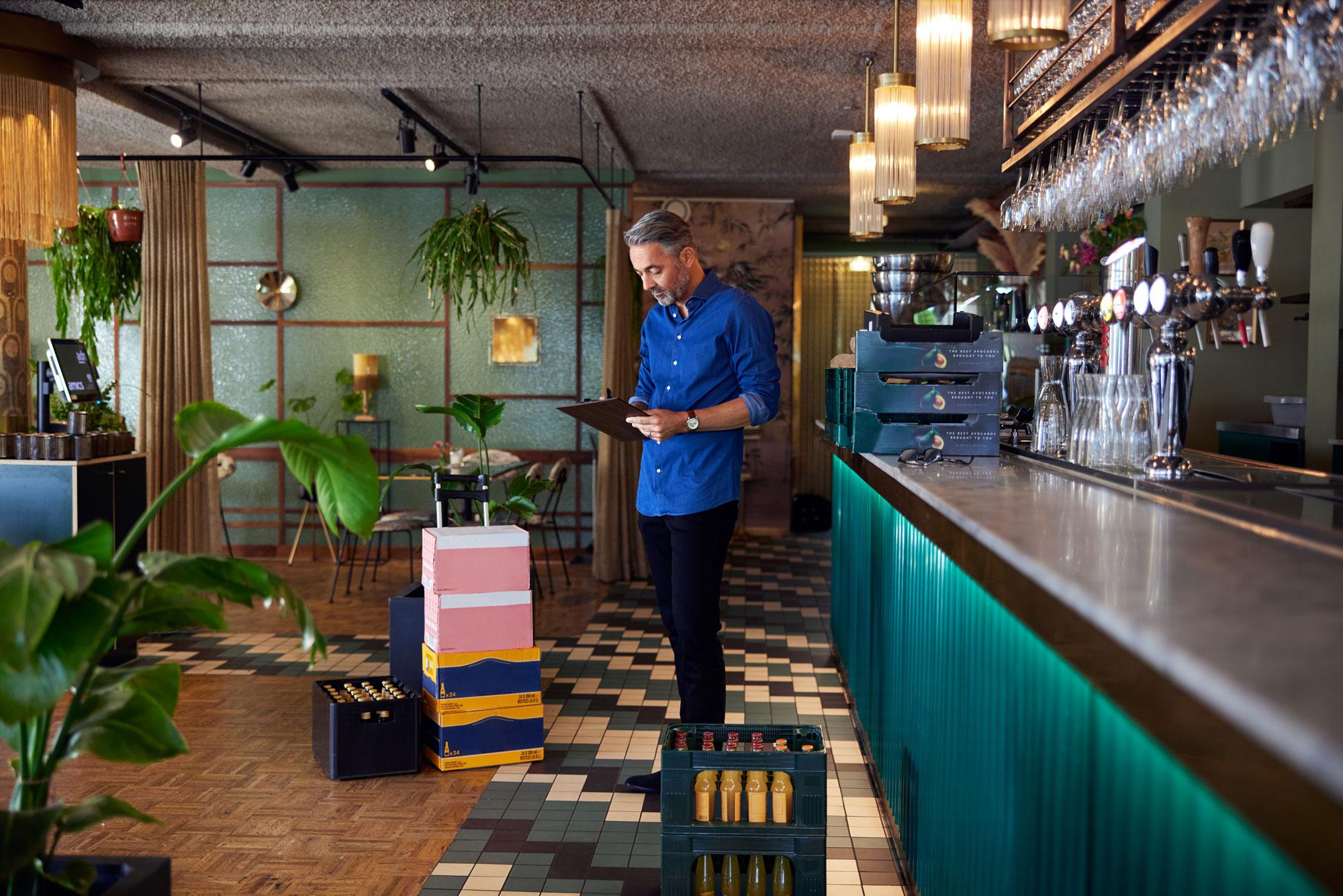 En restaurantmedarbejder modtager kasser med drikkevarer før åbning.