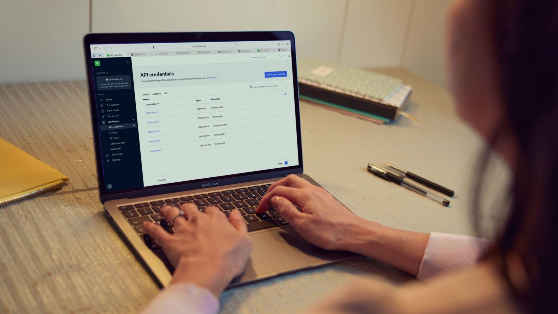 Person using a laptop displaying Adyen API credentials on screen.