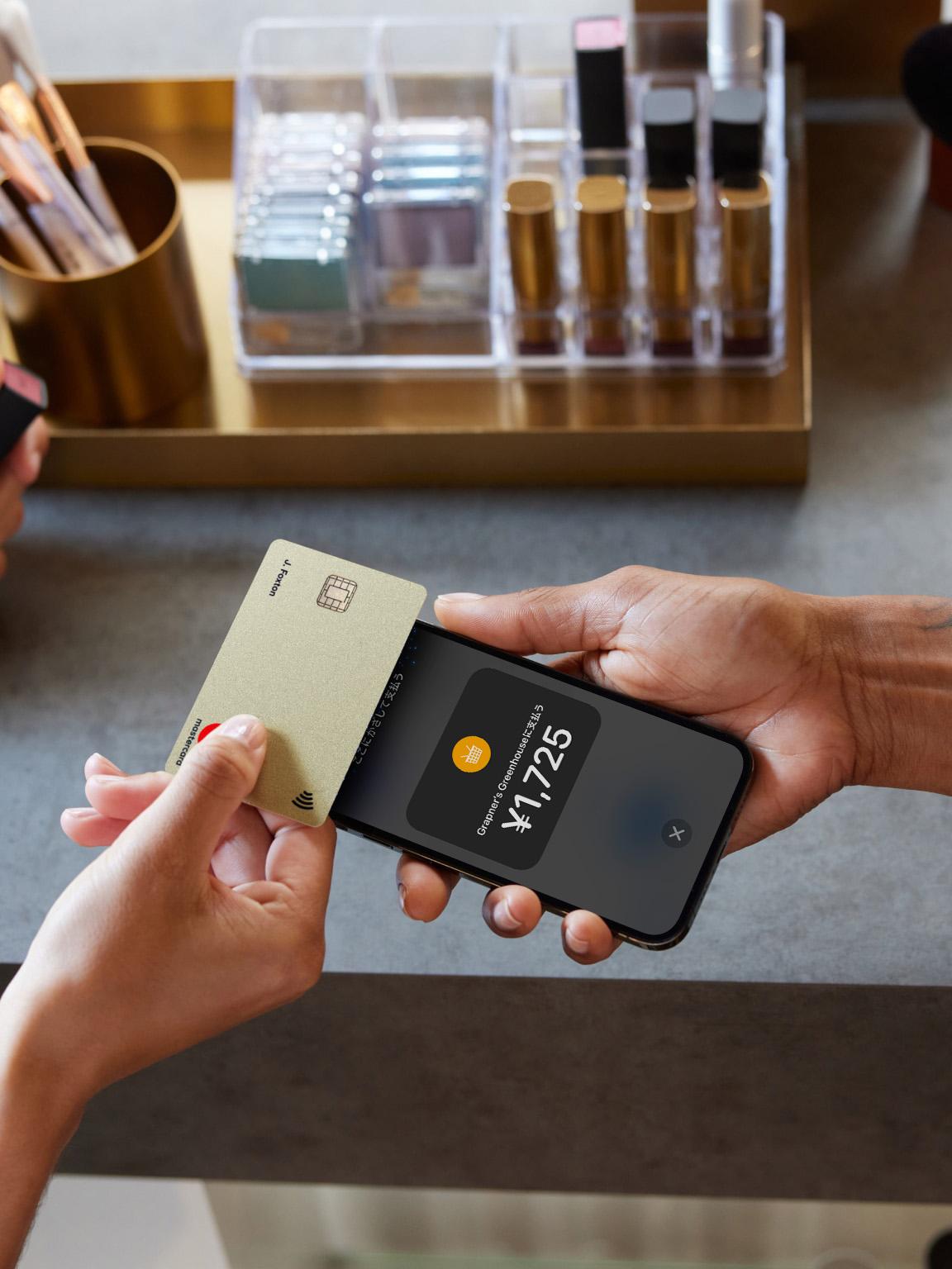 A parson tapping a card on an iPhone with Tap to pay screen in Japanese with an amount in Japanese yen.