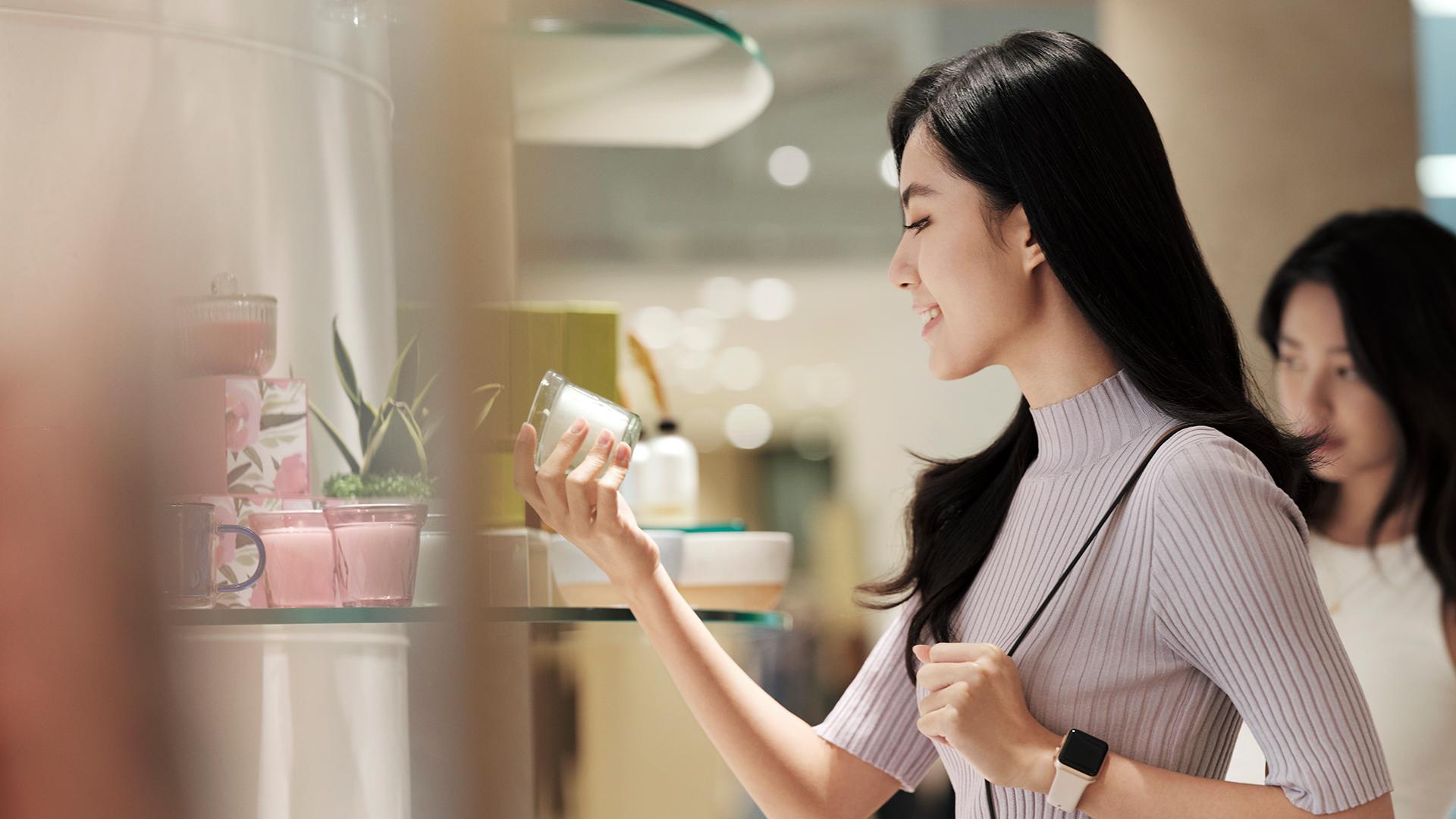 Woman smiling as she examines a product in a brightly lit store.