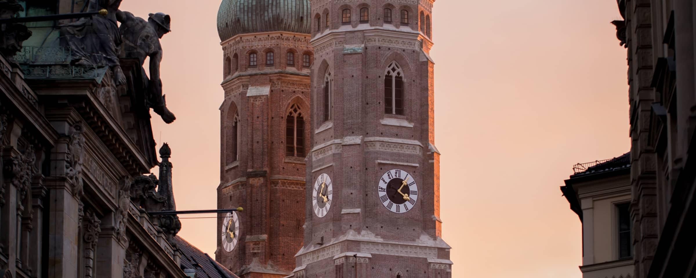 Solnedgangsudsigt over en historisk urtårn med intrikat arkitektur i forgrunden