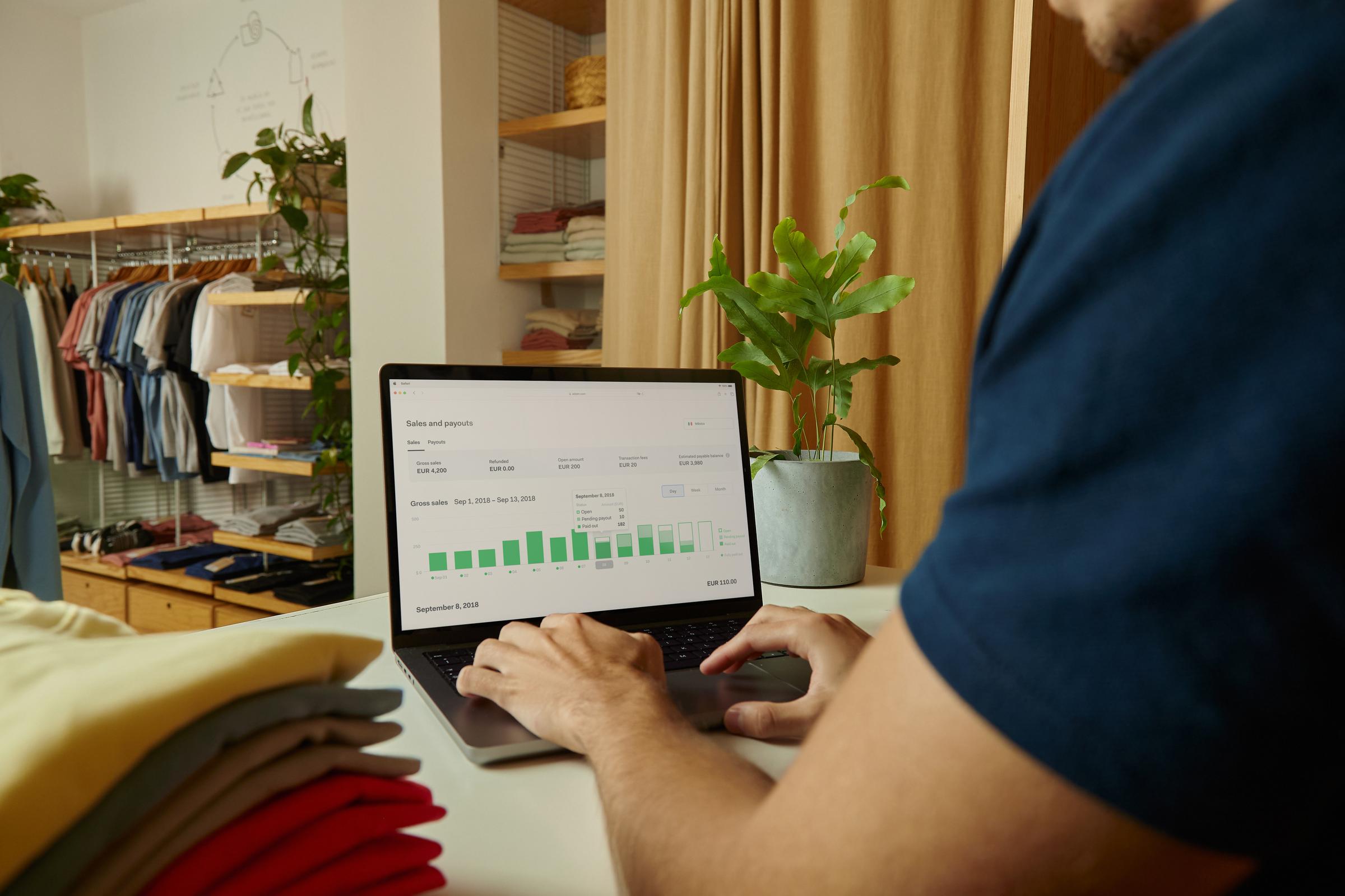Personne utilisant un ordinateur portable avec analyse des ventes et des paiements Adyen à l'écran.