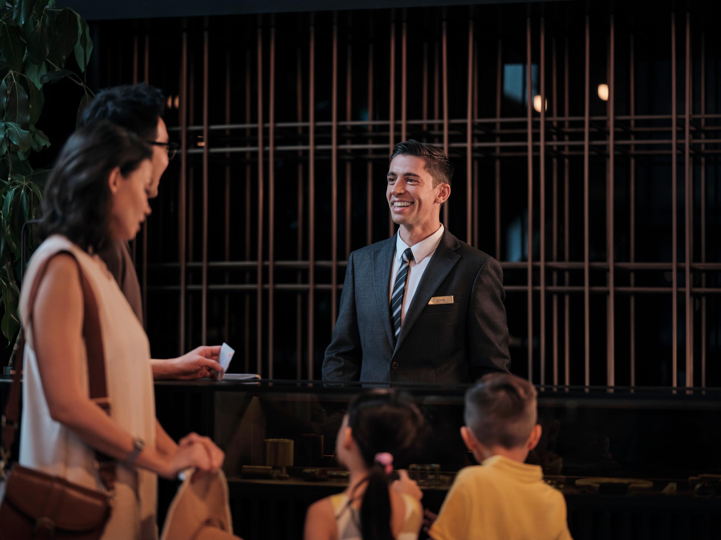 Una familia con niños que se registra en la recepción de un hotel.