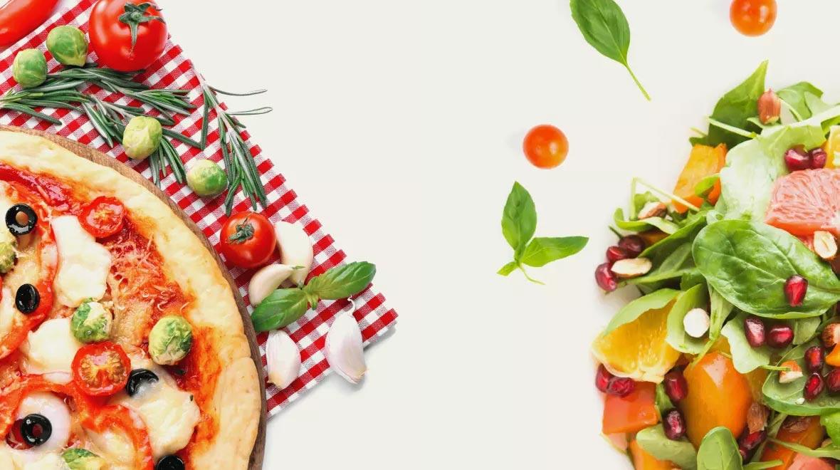 Metade de uma pizza ao lado de uma salada mista fresca com vários legumes em um fundo branco.