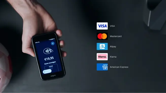 Osoba držící smartphone s platebním rozhraním Adyen zobrazujícím poplatky 19,95 € a více platebních možností.