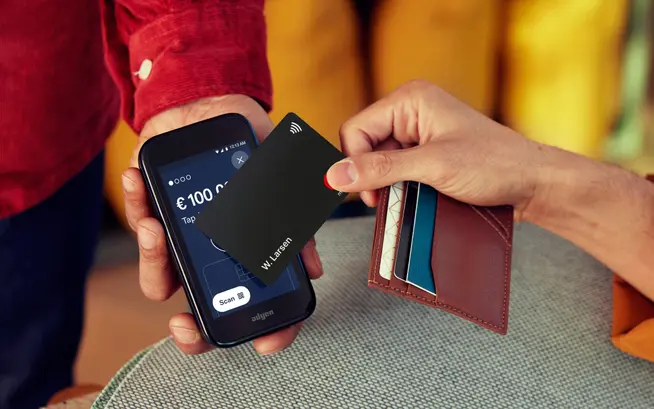 Person som taper en kontaktløs kort på en mobil betalings-terminal som viser Adyen-betalings-skjermen
