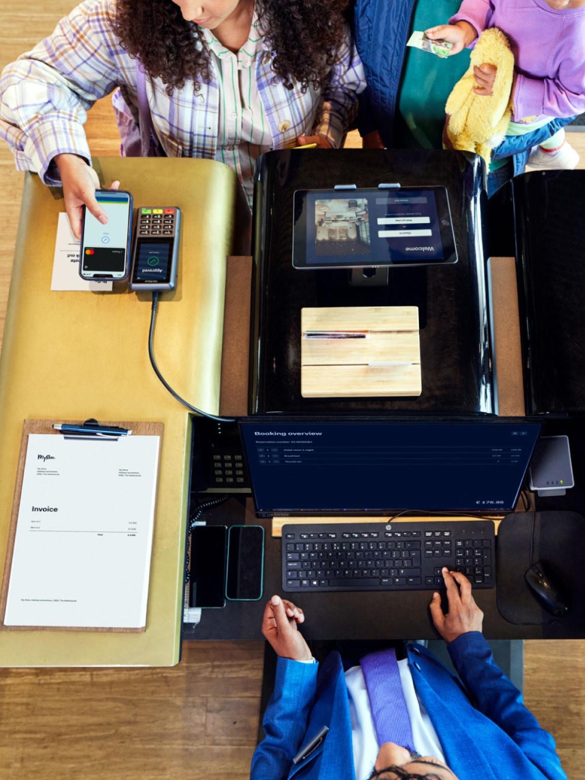 Person using a smartphone to make a contactless payment at a checkout terminal with Adyen POS system.