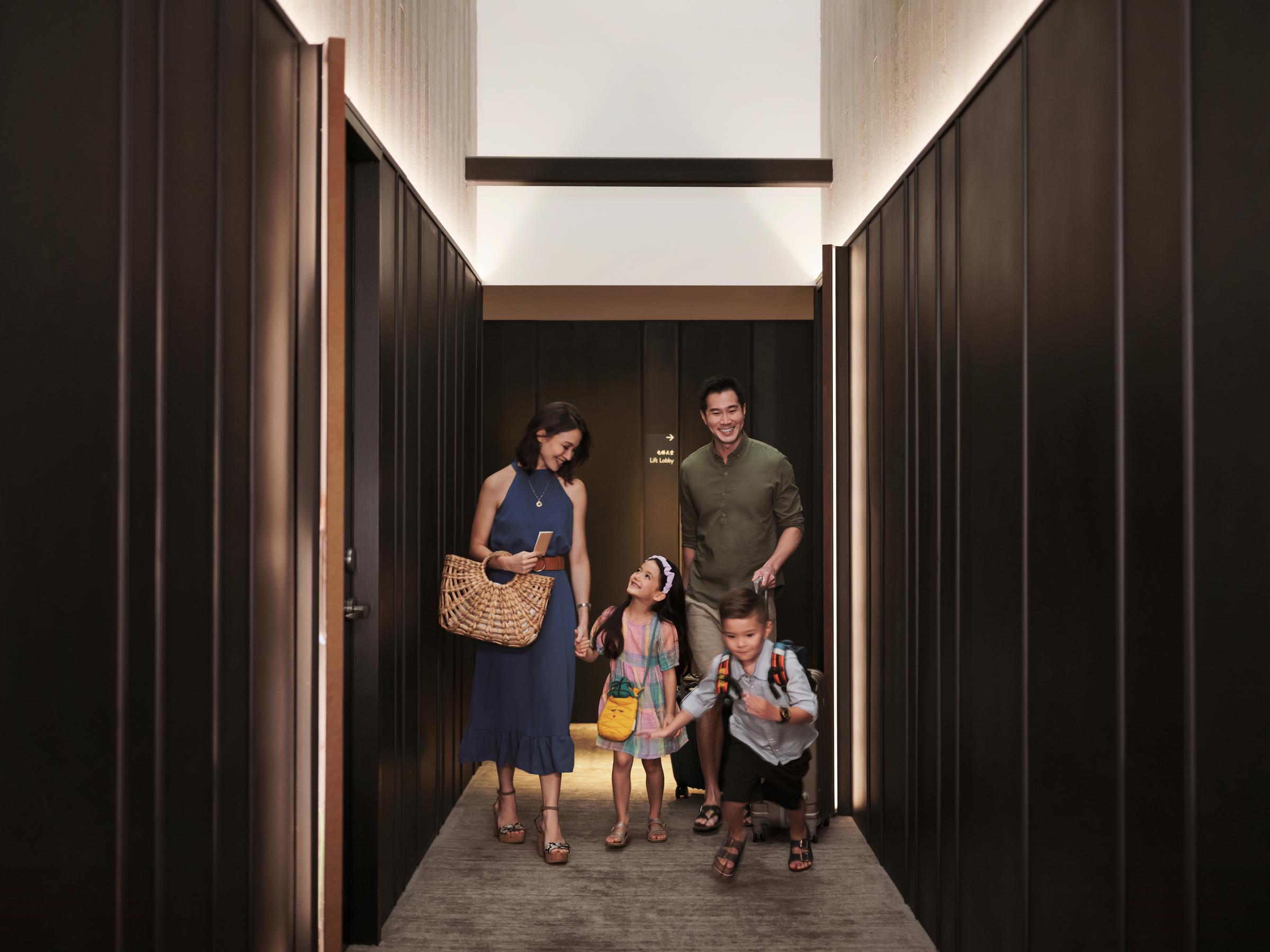 Una familia con hijos, caminando por el pasillo del hotel después de registrarse en su habitación.