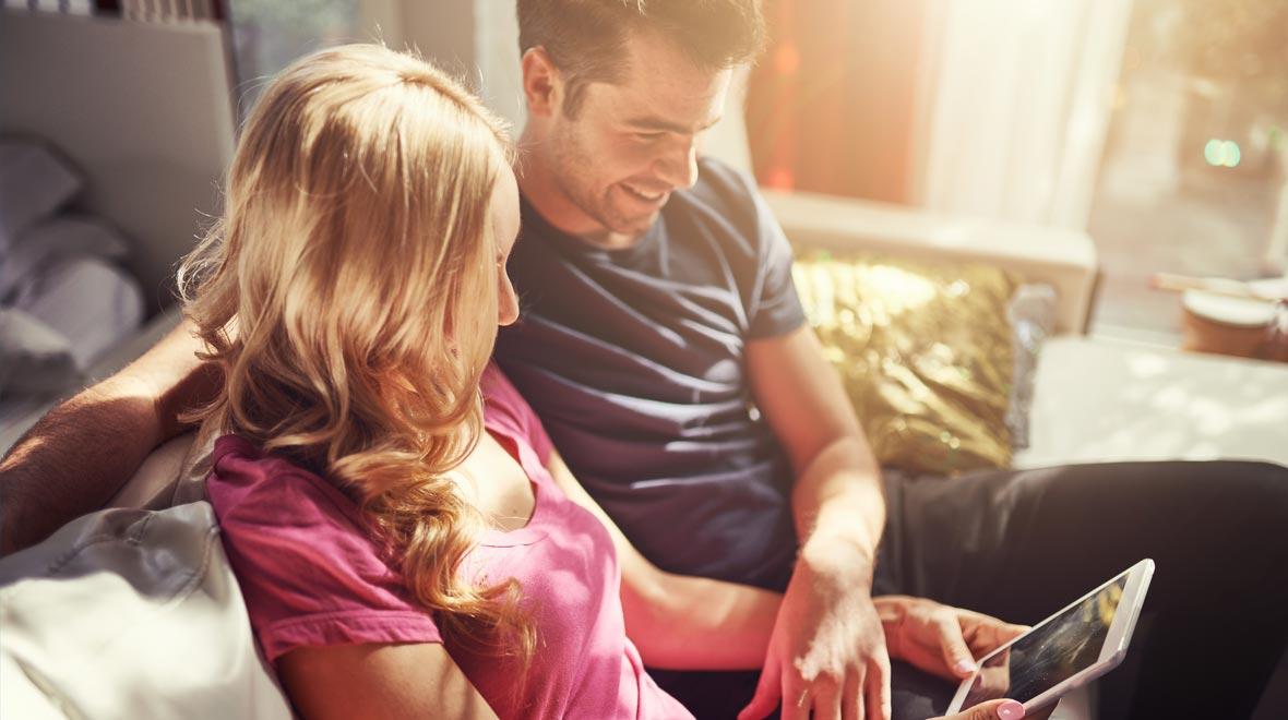 Deux personnes assises ensemble et regardant une tablette dans une pièce bien éclairée.
