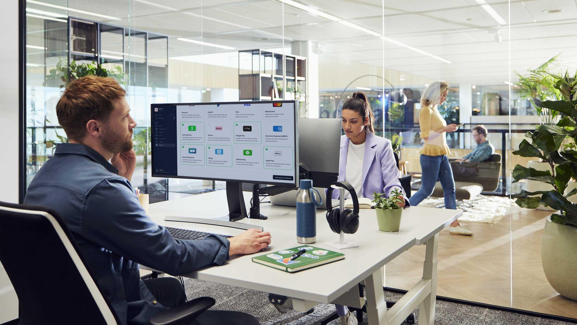 Man in office is working on his ecommerce site on a big computer screen.