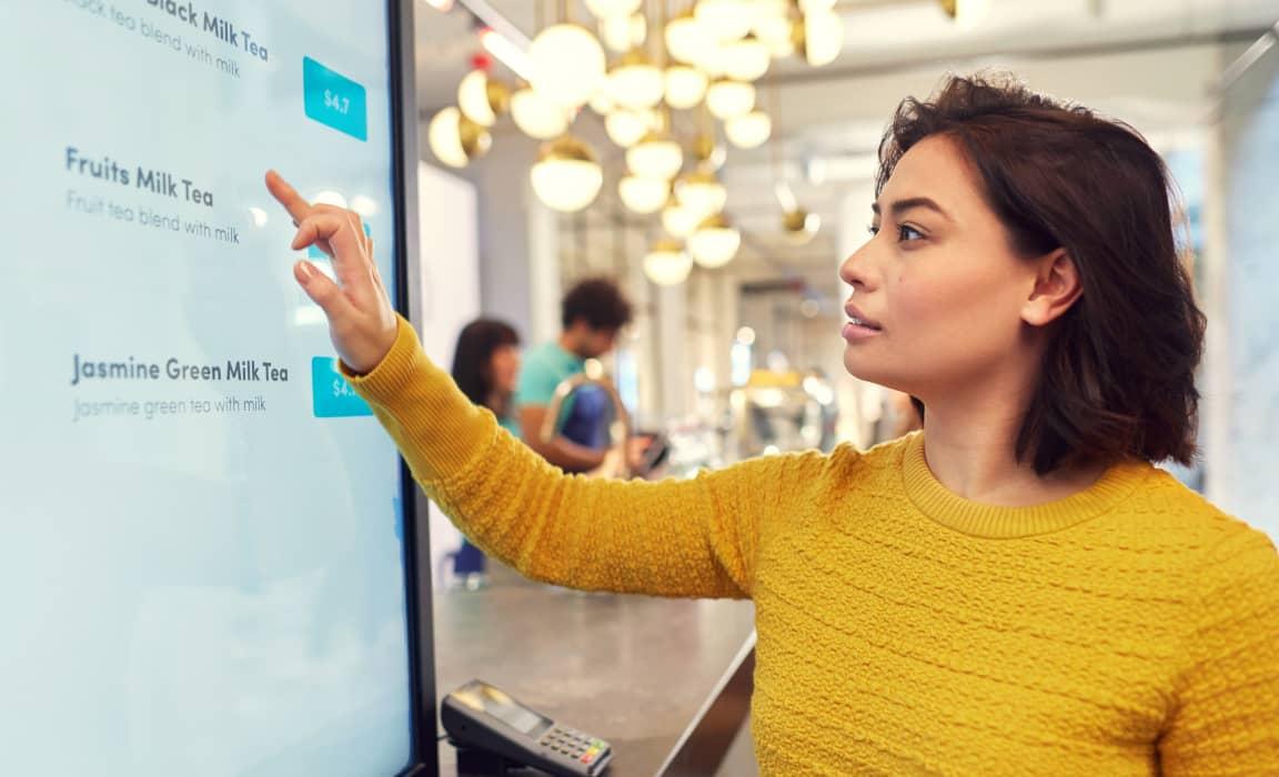 Women touching screen to place order in restaurant