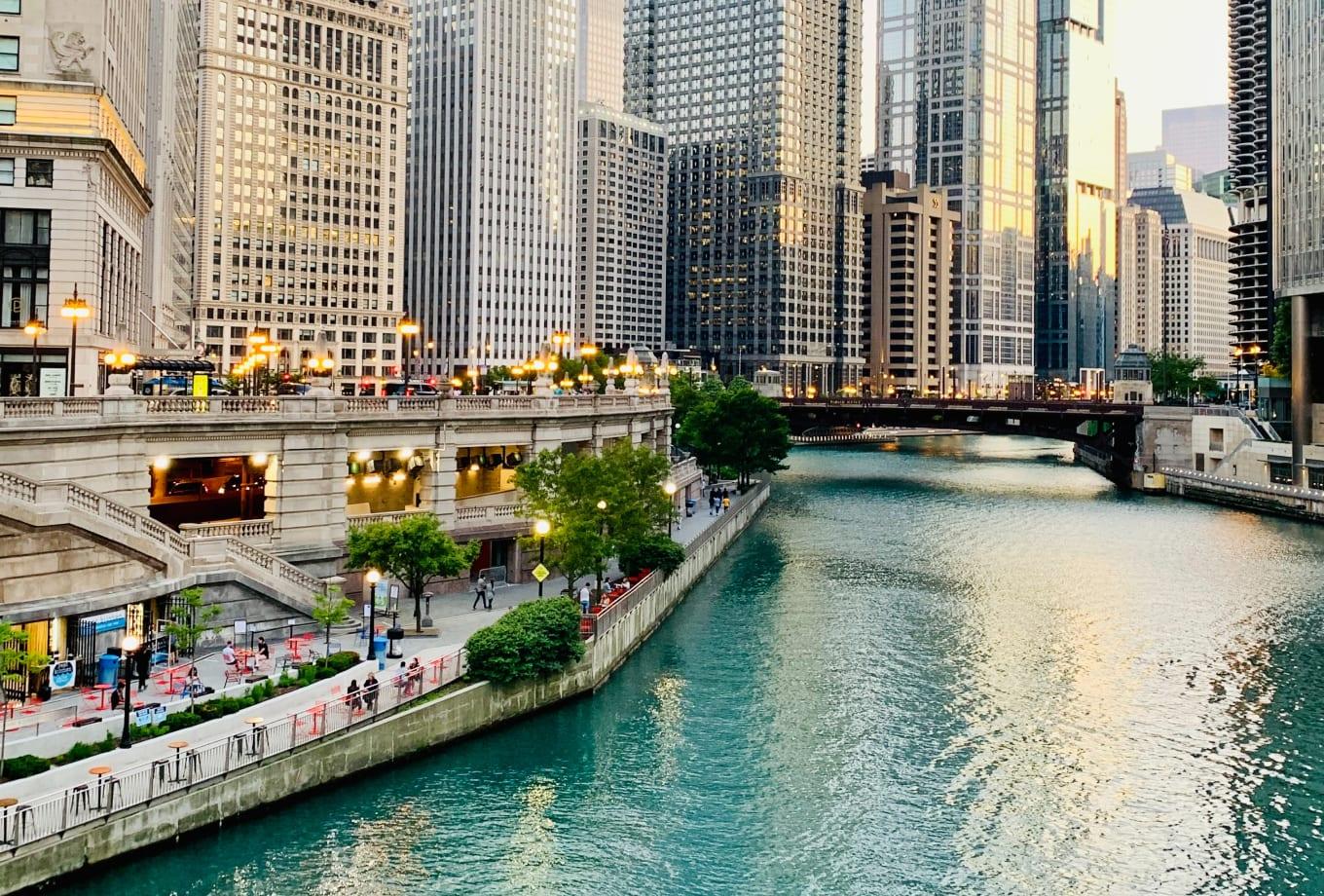 Paisaje urbano del centro al anochecer con edificios iluminados y paseo fluvial.