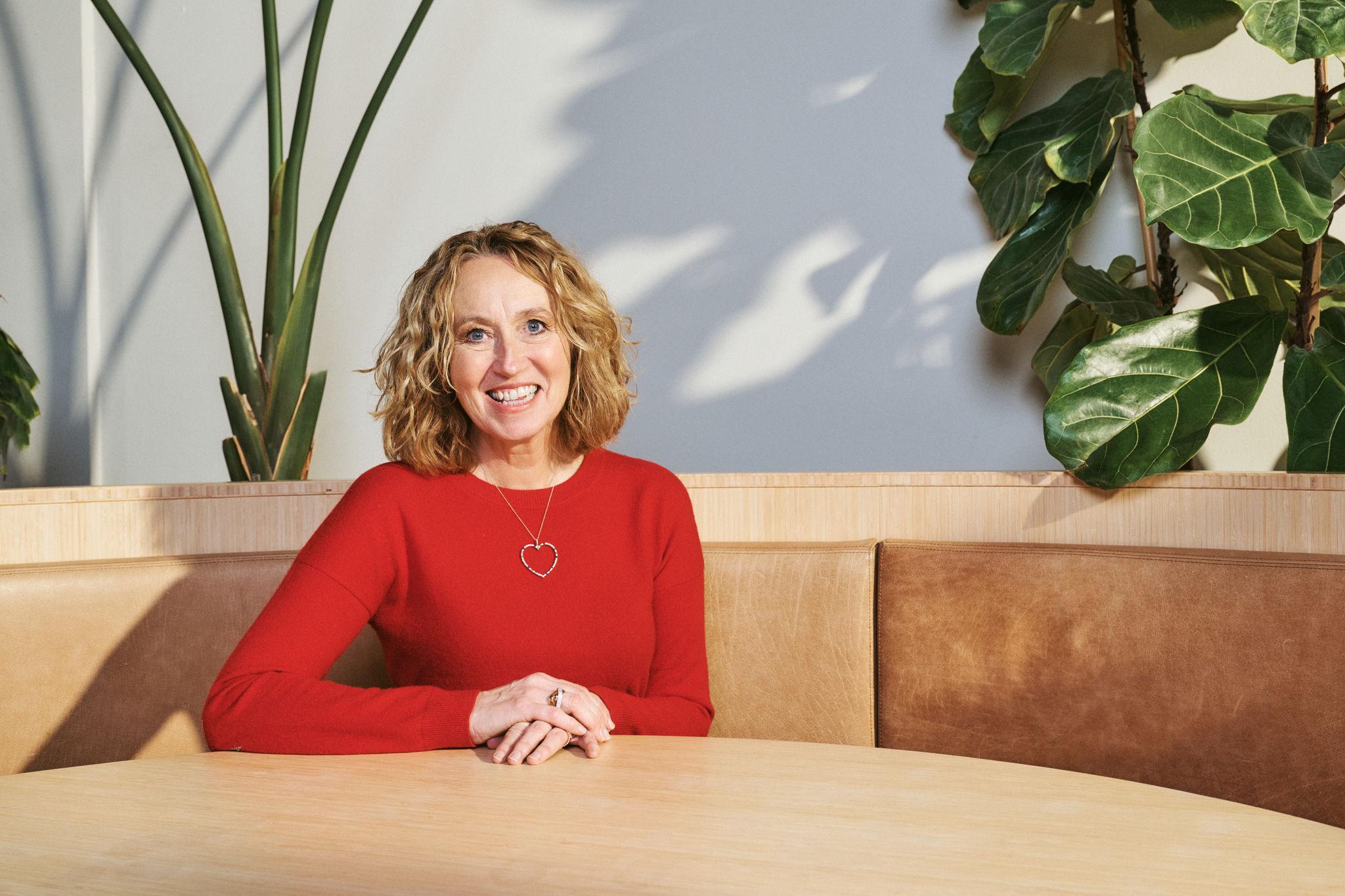 Adyen team member in a red sweater seated at a table in a modern workspace