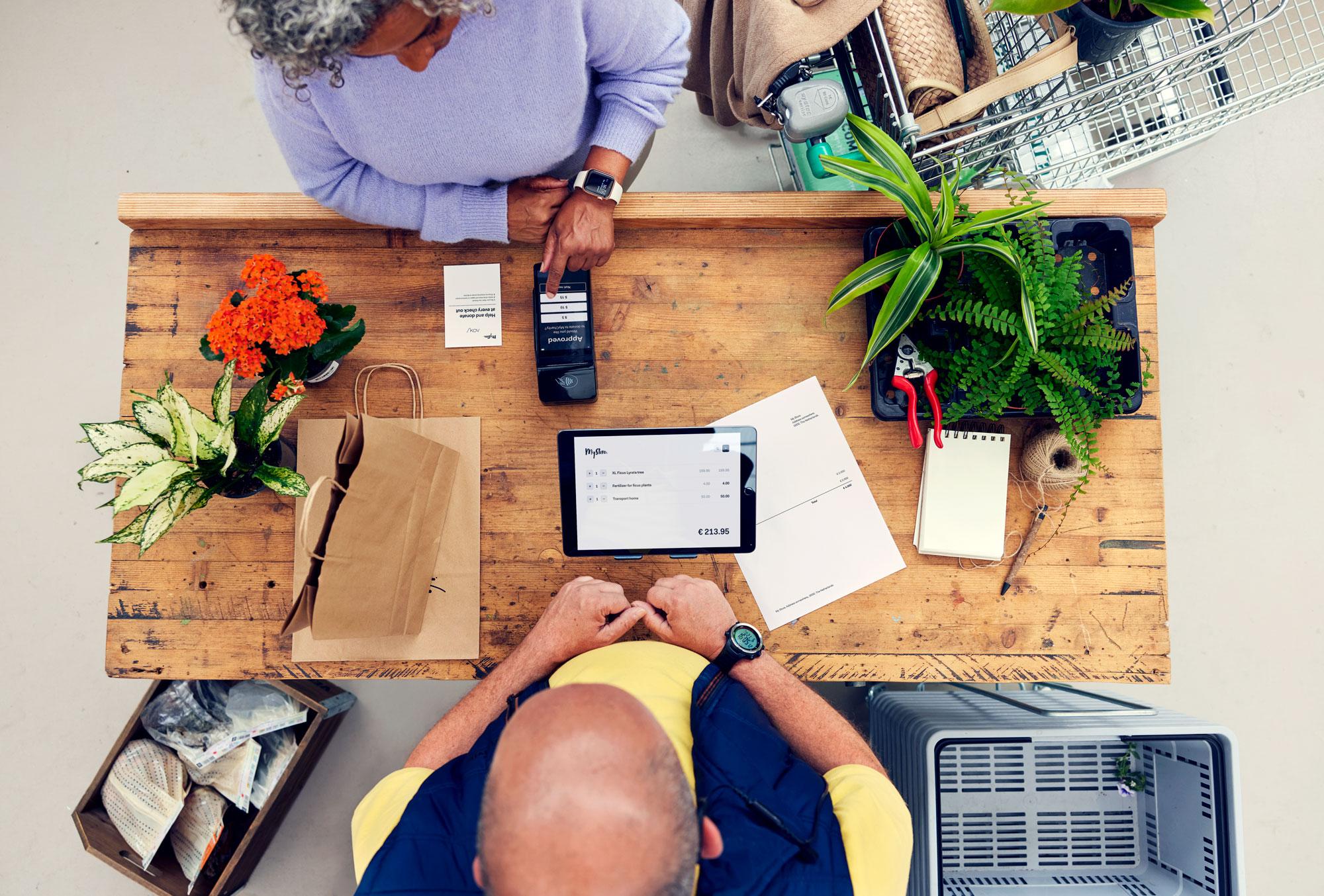 A customer at a counter in a garden centre paying for plants and making a donation on Adyen's S1F2 terminal.