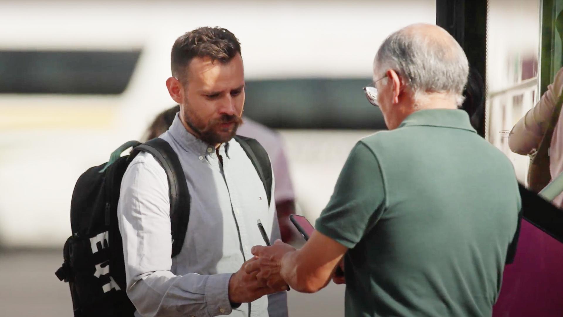 Dos hombres estrechando la mano en una calle concurrida.