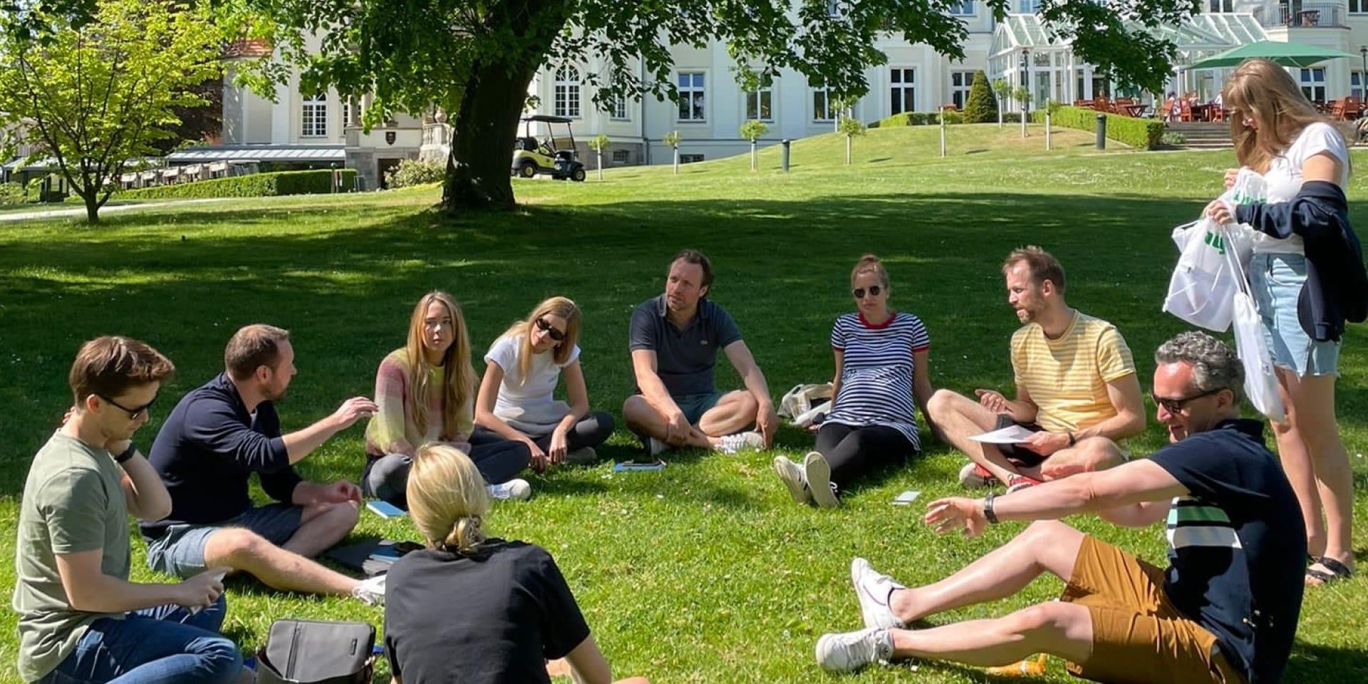 Eine Gruppe Mitarbeitende von Adyen Deutschland sitzen auf einer Wiese