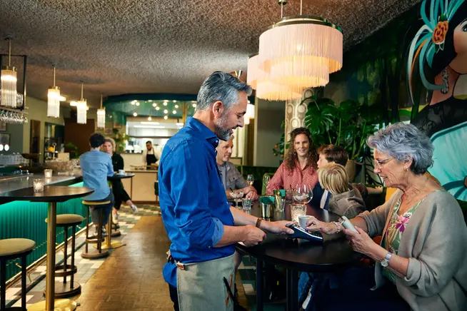 Una donna in un ristorante che paga con carta utilizzando il terminale V400m di Adyen