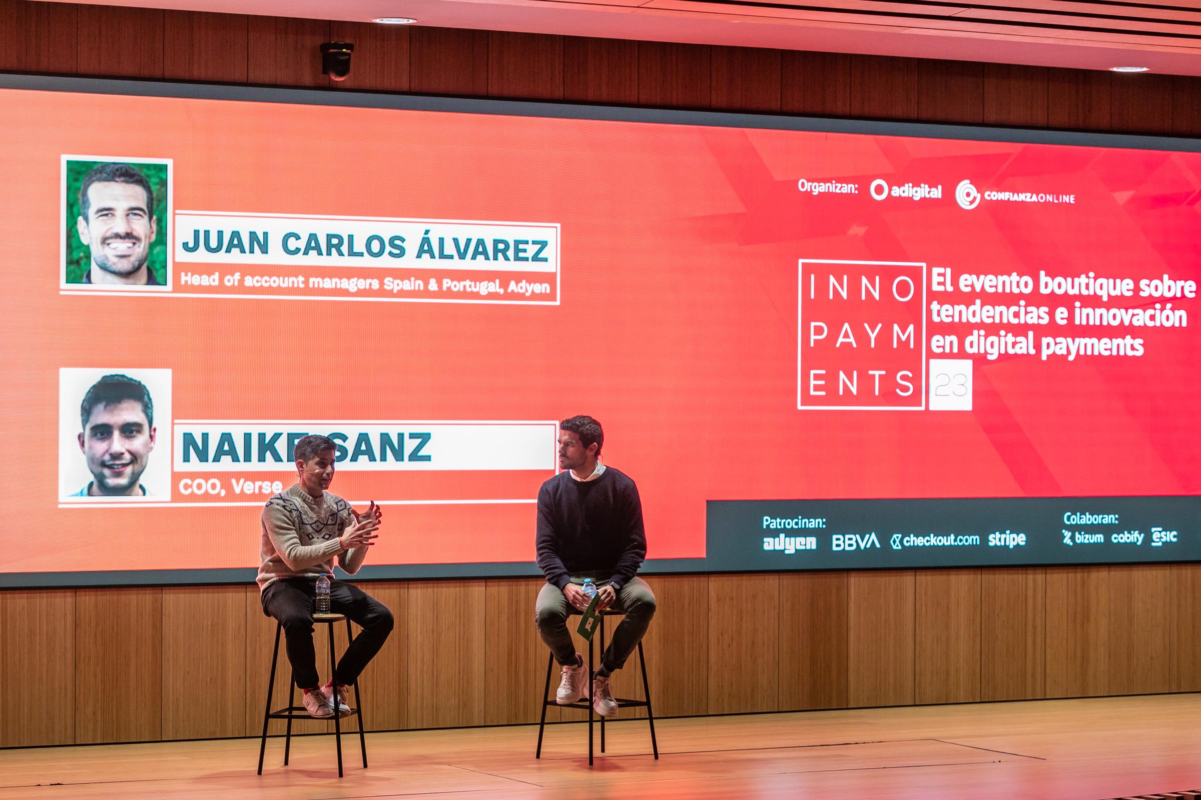 Dos ponentes en una conferencia de INNOPAYMENTS con el jefe de gestores de cuentas de Adyen para España y Portugal en la pantalla.