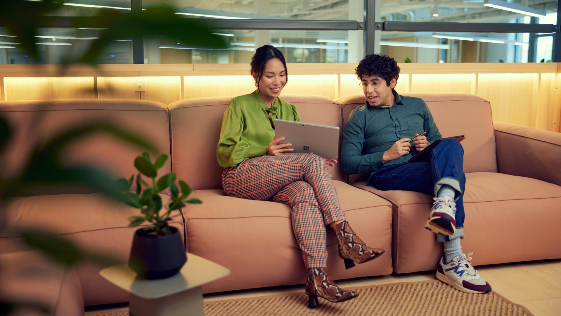 Zwei Personen auf einem Sofa schauen auf einen Laptop