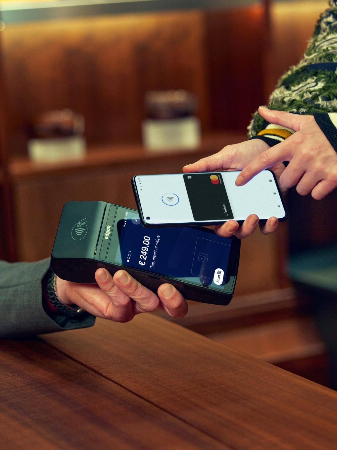 Dwie osoby realizujące płatność mobilną przy użyciu technologii transakcji bezdotykowej Adyen