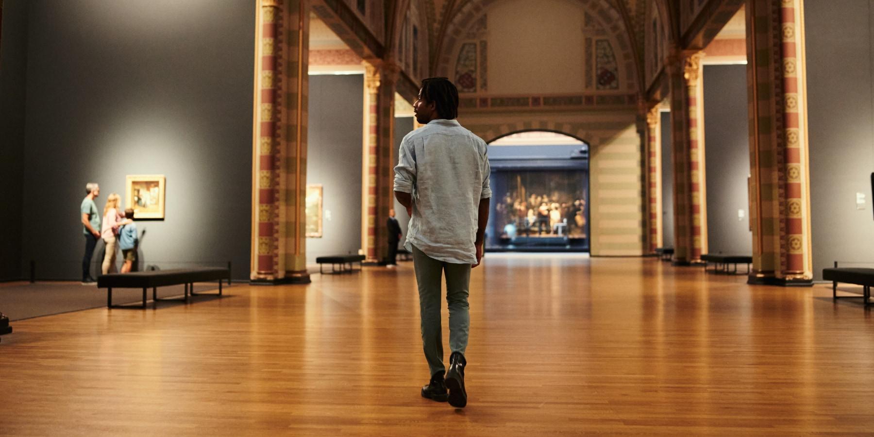 Personne debout dans une galerie d'art observant des peintures.