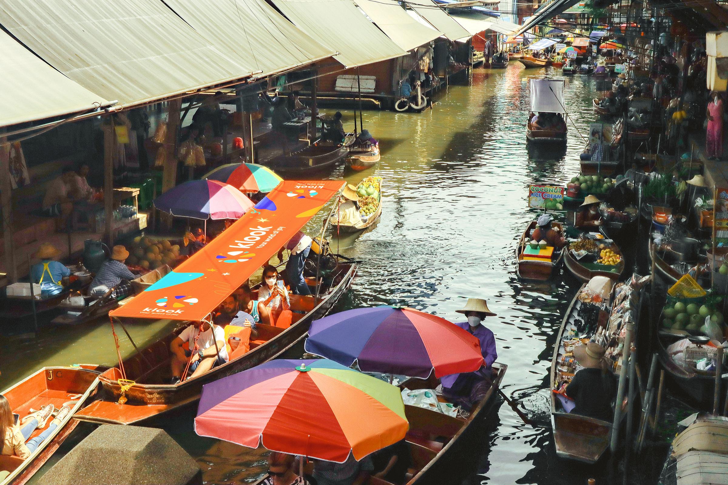 A floating market in Thailand with a Klook boat on the left edge.