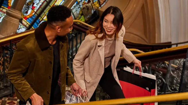 Two people happily shopping with a bag from a recognizable brand.