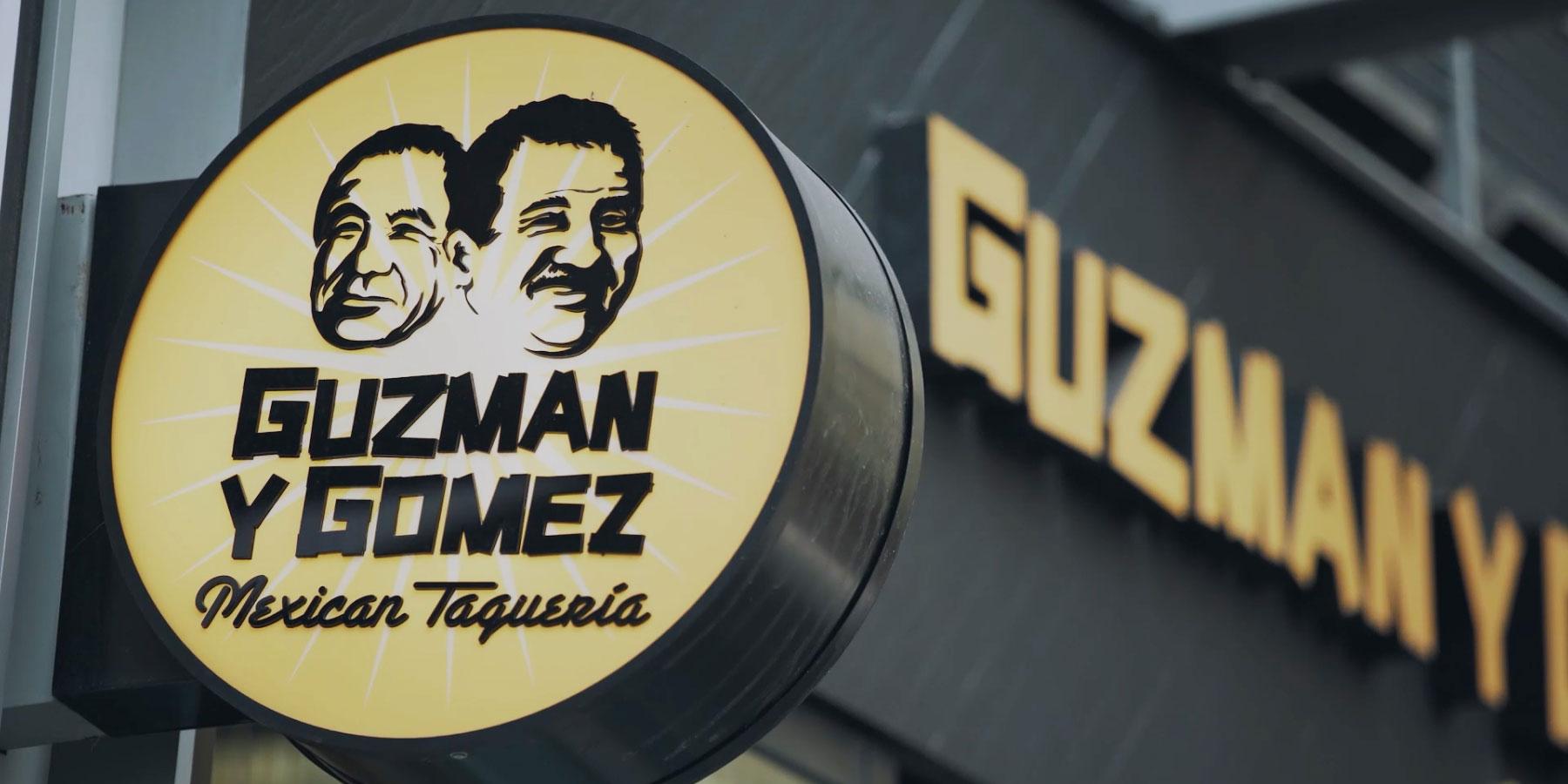 Circular sign with 'Guzman y Gomez Mexican Taqueria' and two smiling faces