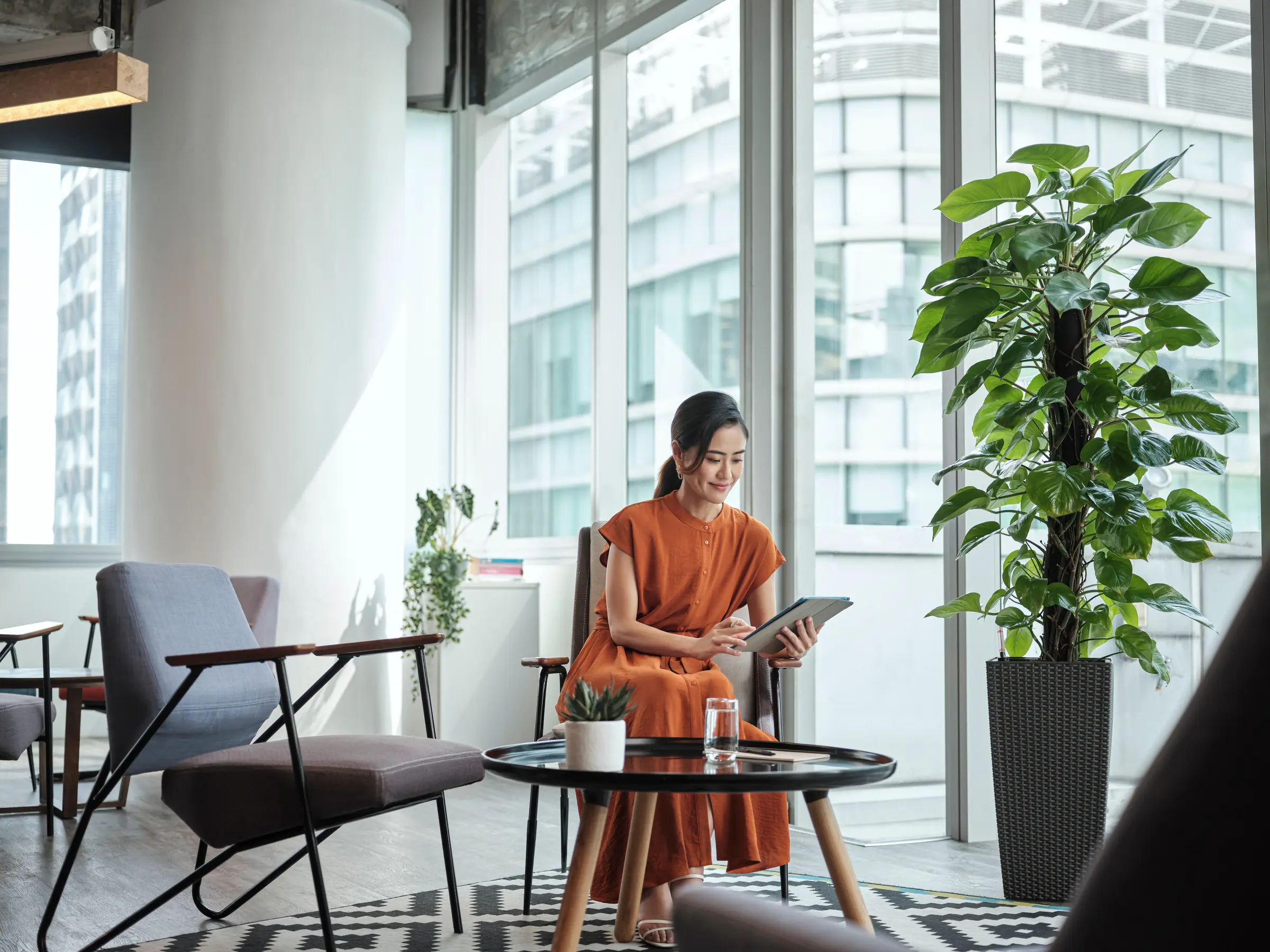 A woman sitting on a low chair holding her ipad