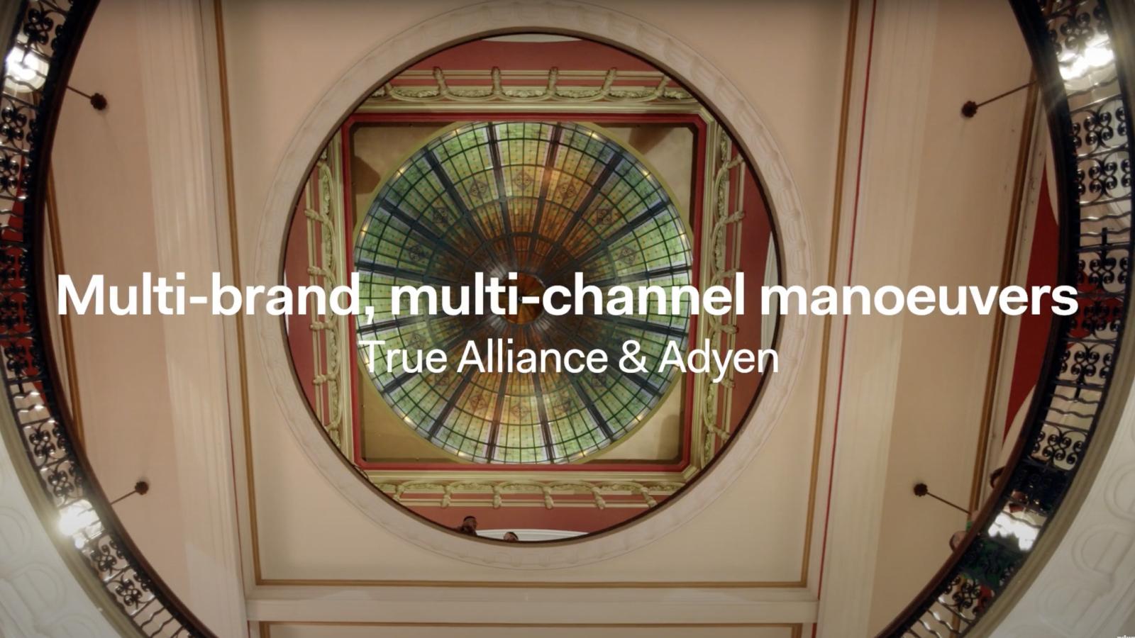 Stained glass ceiling inside a building with promotional text for True Alliance & Adyen.