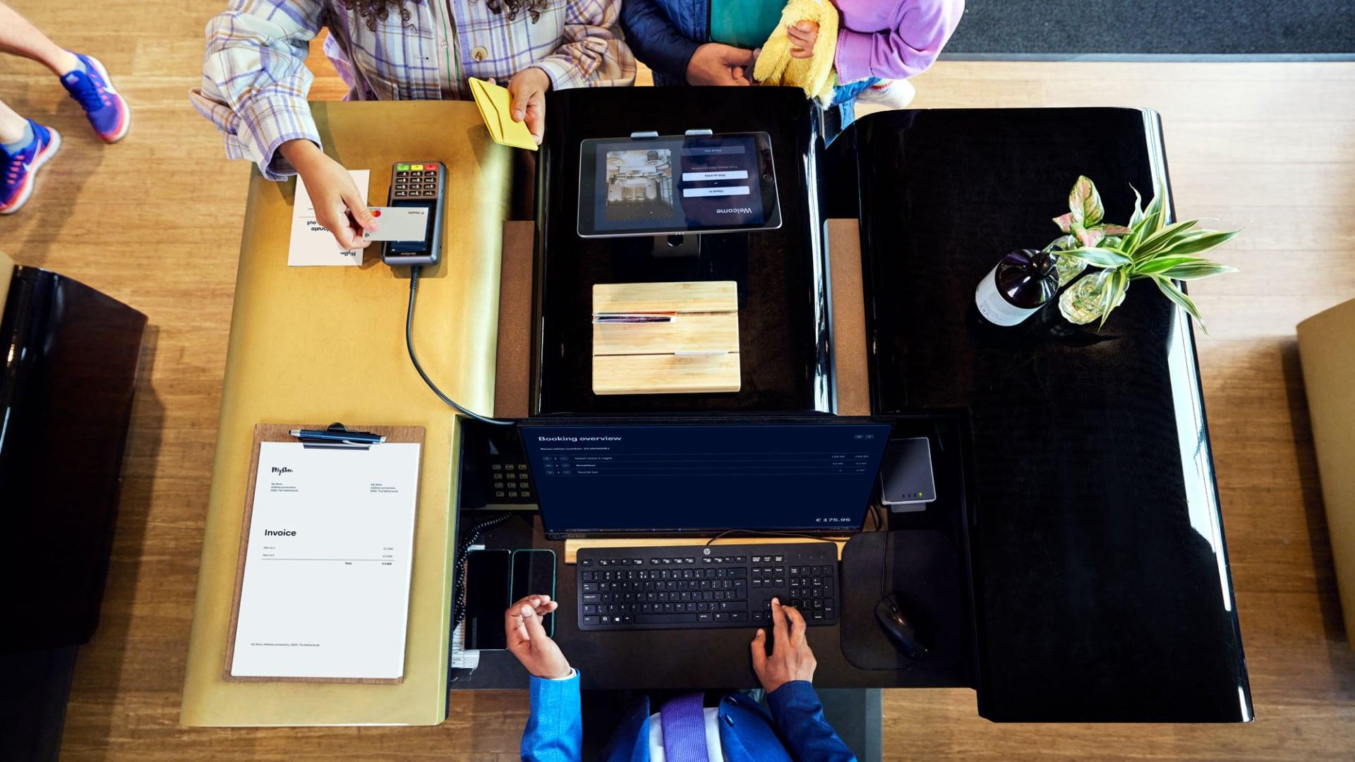 Top view of a checkout counter with a customer using an Adyen payment terminal.
