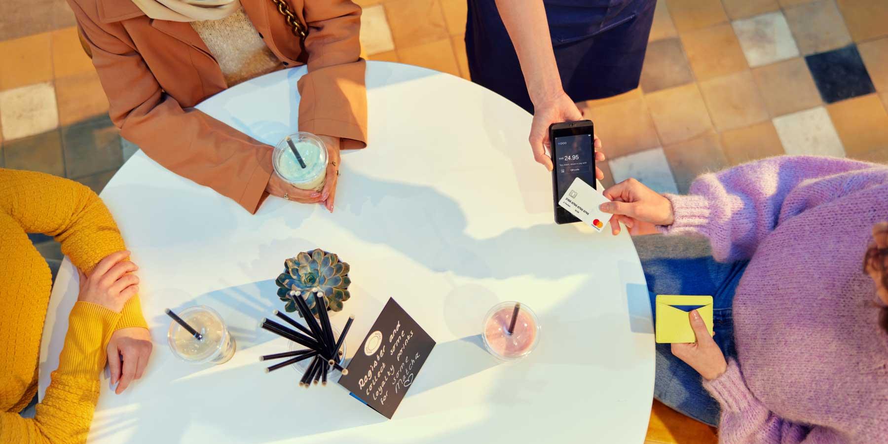 Pessoa usando terminal de pagamento Adyen para processar uma transação de cartão em um café