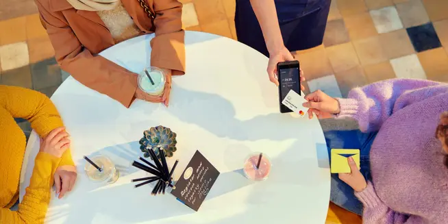 Persona che utilizza il terminale di pagamento Adyen per elaborare una transazione con carta in un caffè