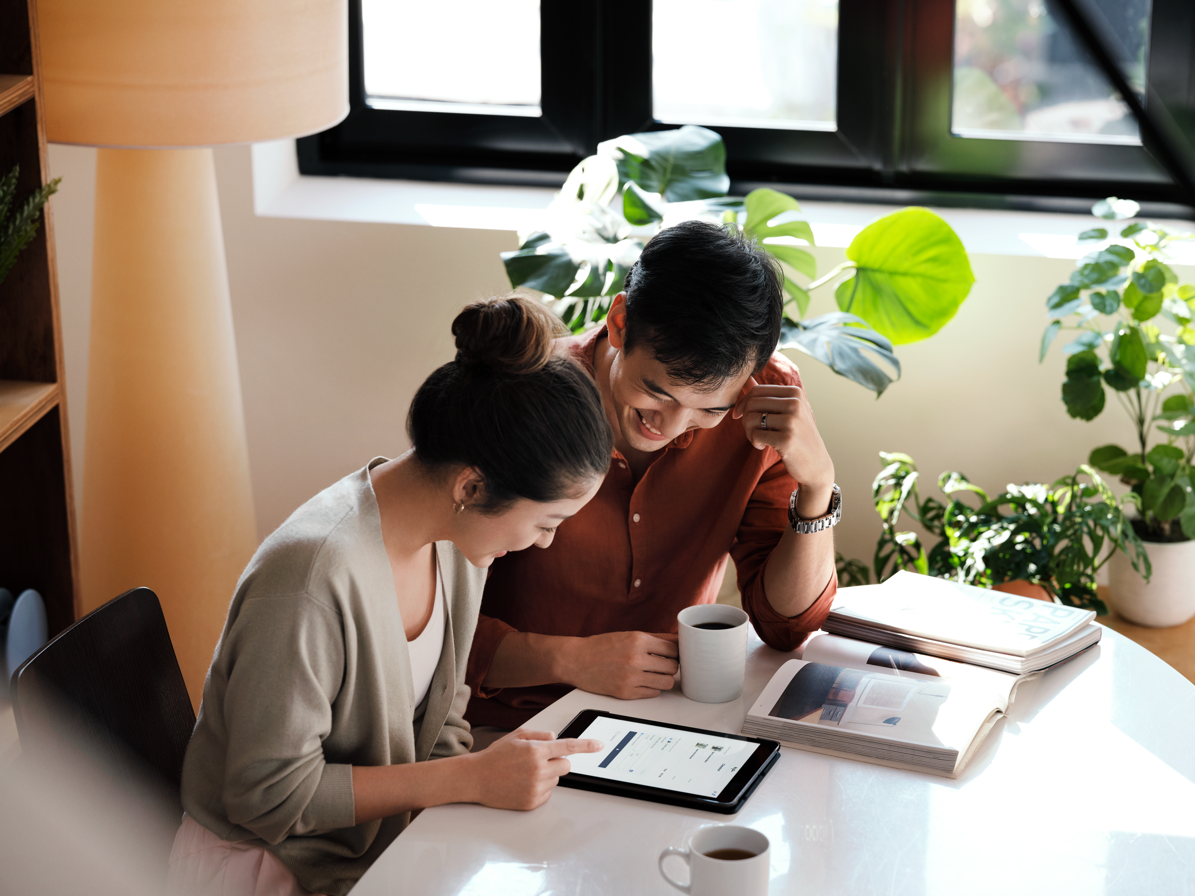 A smiling couple sitting at a table and looking at a checkout screen on the tablet.