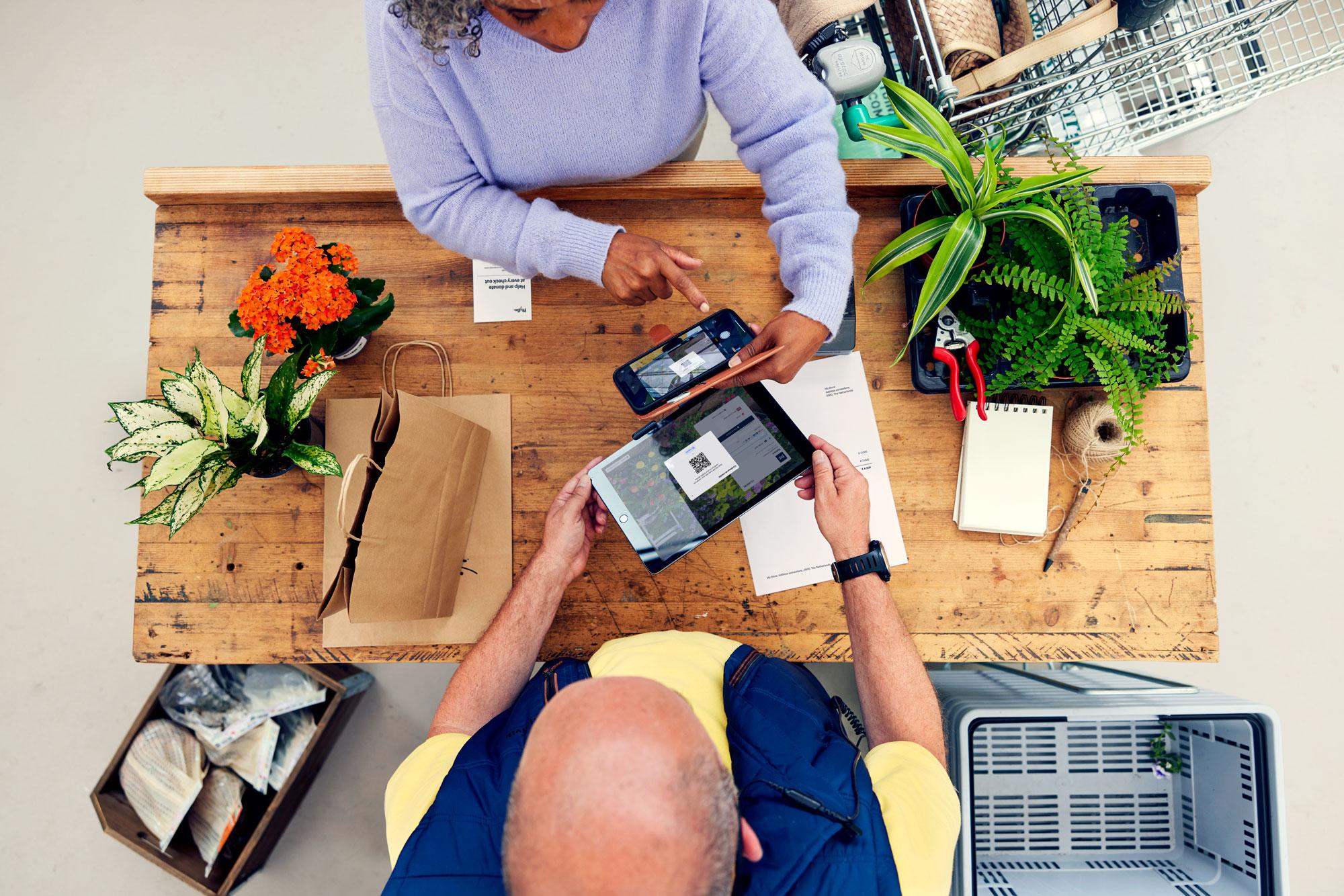 Um cliente no balcão de um centro de jardinagem paga plantas usando Adyen's Pay by link