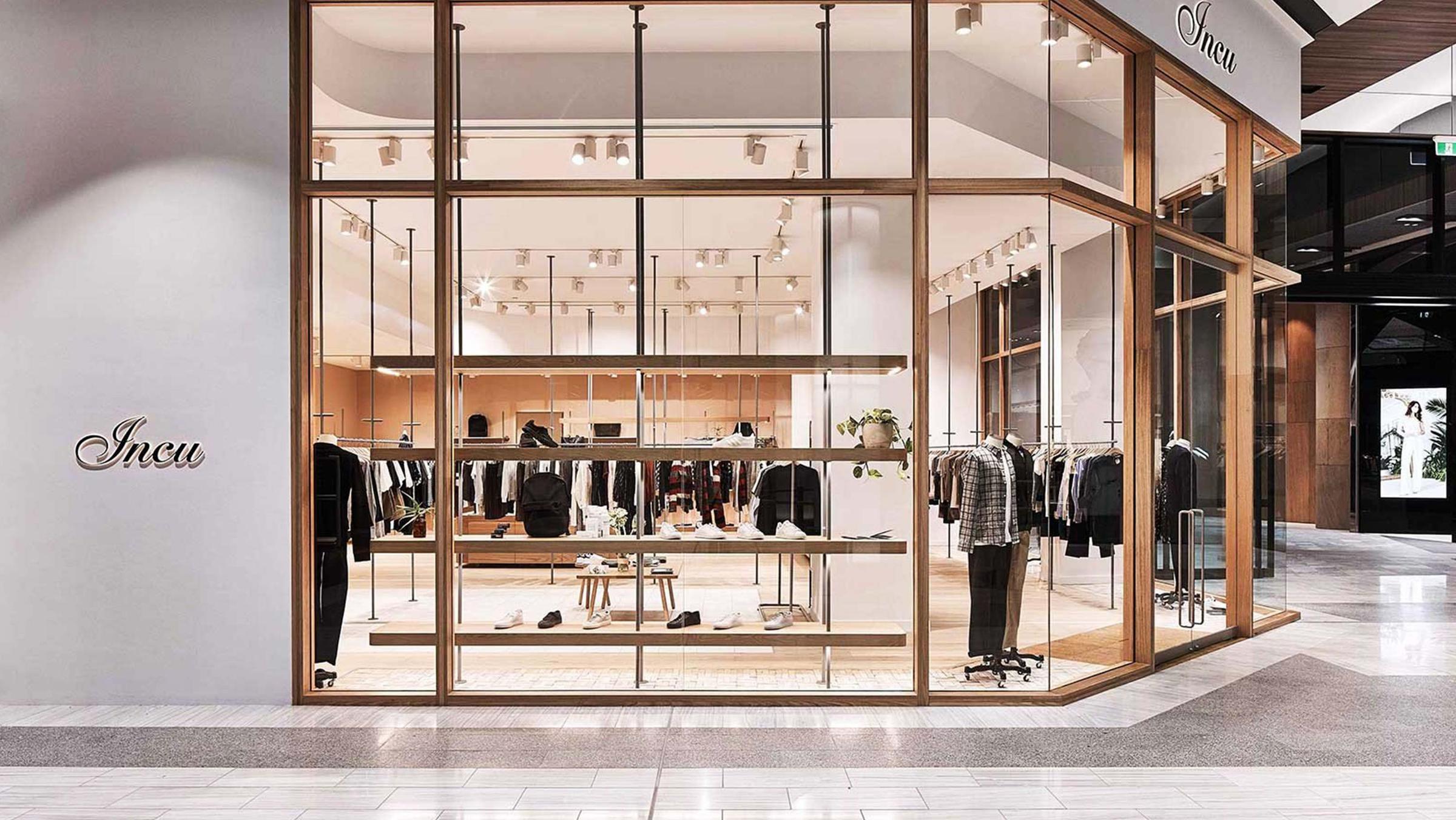 Modern clothing store interior with apparel displayed on racks and shelves.