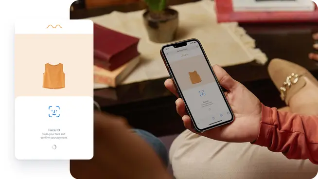 Eine Person sitzt mit dem Telefon in der Hand, auf dem Bildschirm ist die Face ID-Autorisierung