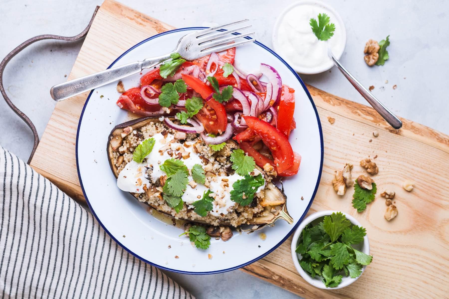 Un plato de berenjena rellena de cuscús con yogur, tomates, cebollas y hierbas.