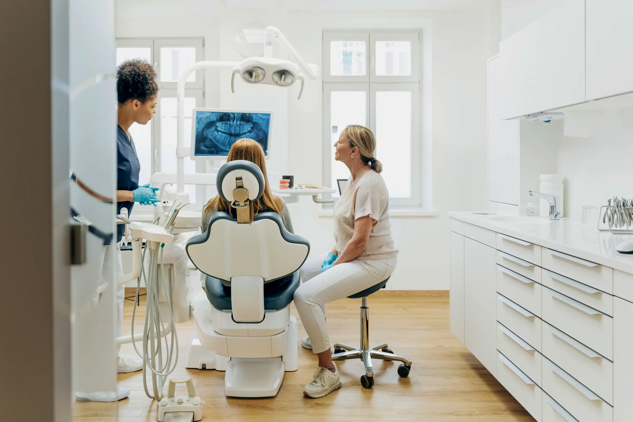 A dentist and her dental assistant looking at an x-ray with the patient