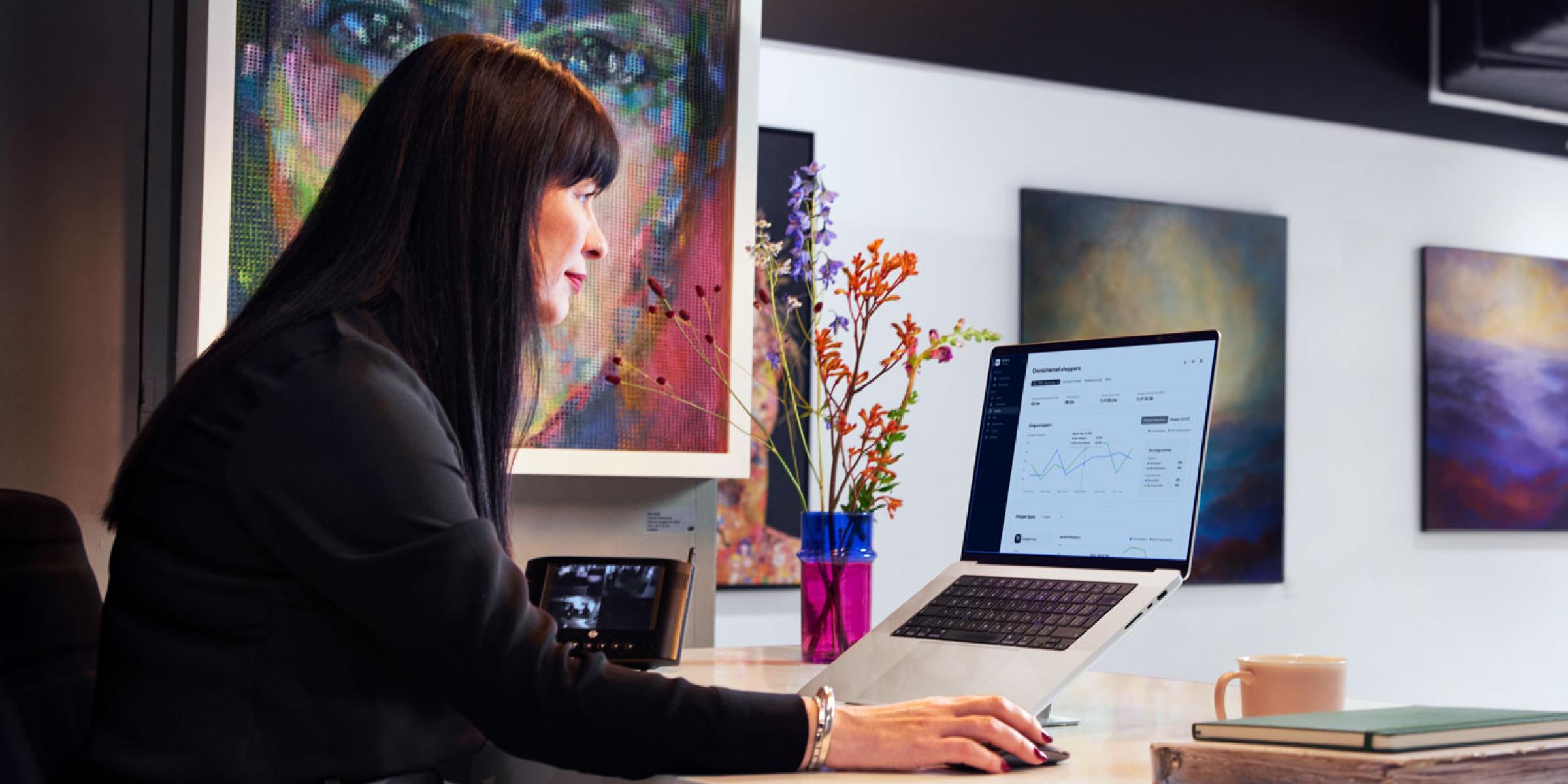 Businesswoman analyzing Adyen product data on laptop screen in a modern office.