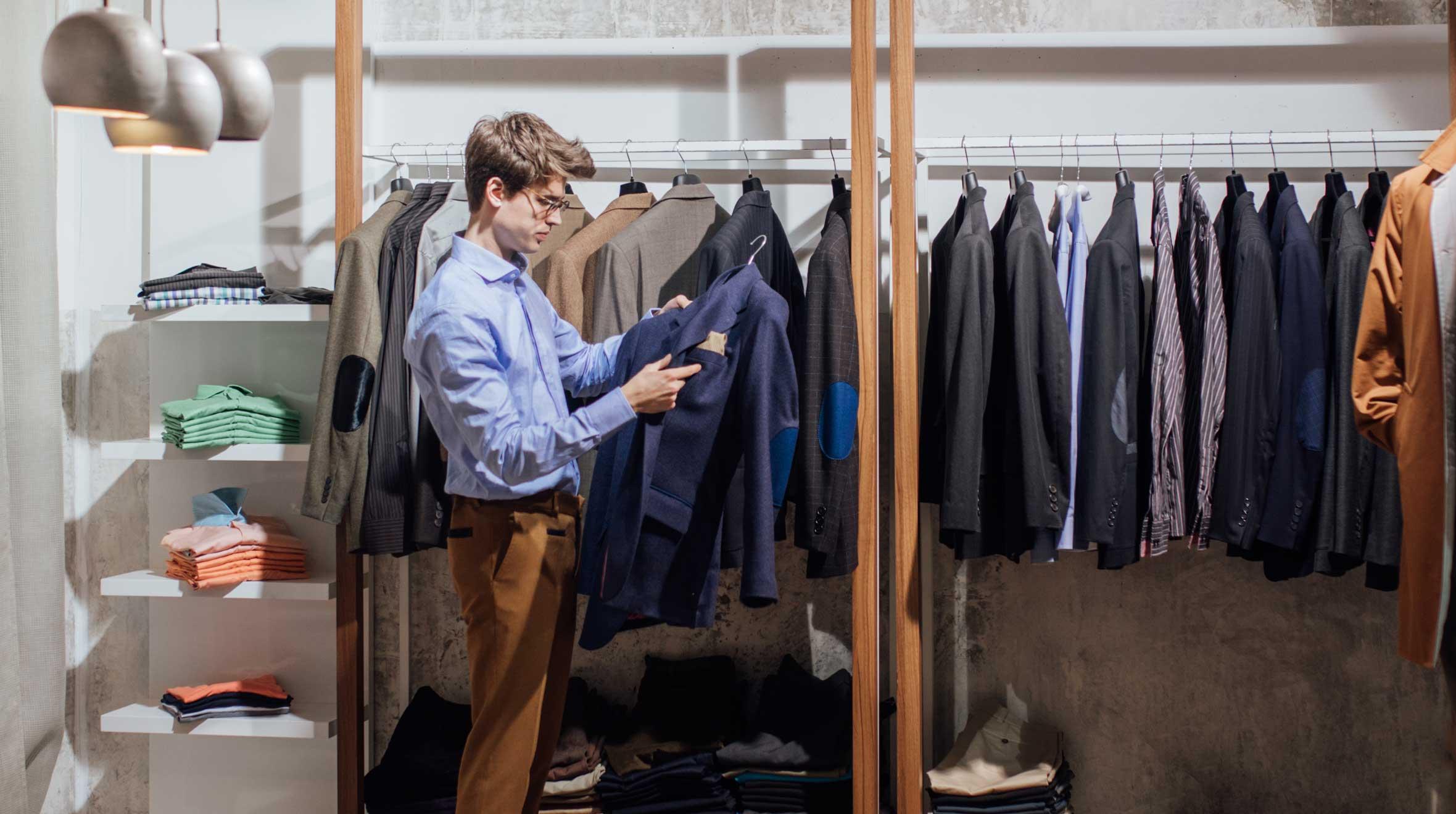 Homme examinant une veste dans un magasin de vêtements moderne.