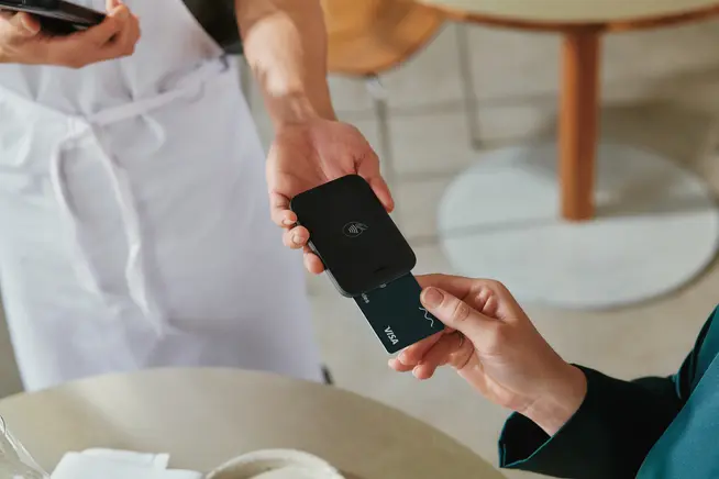 Une femme dans un restaurant payant des repas en tapant une carte VISA sur le terminal NYC1 d'Adyen.