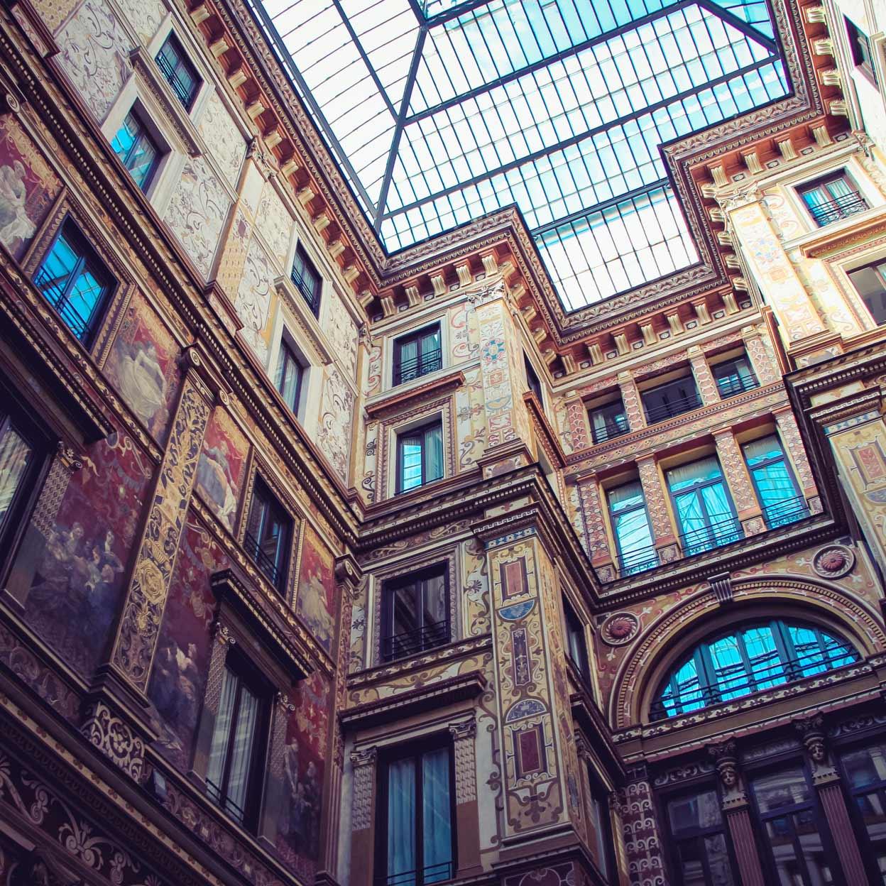 Atrio ornamentado con paredes con frescos y techo de vidrio.