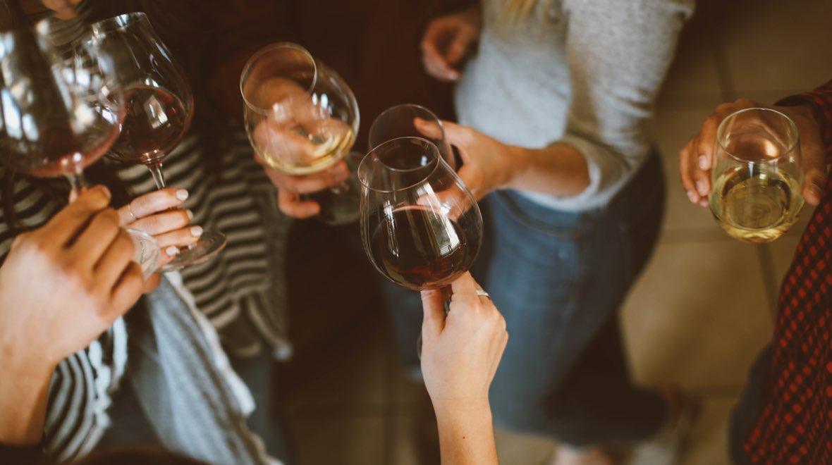Um grupo de pessoas brindando com taças de vinho tinto e branco