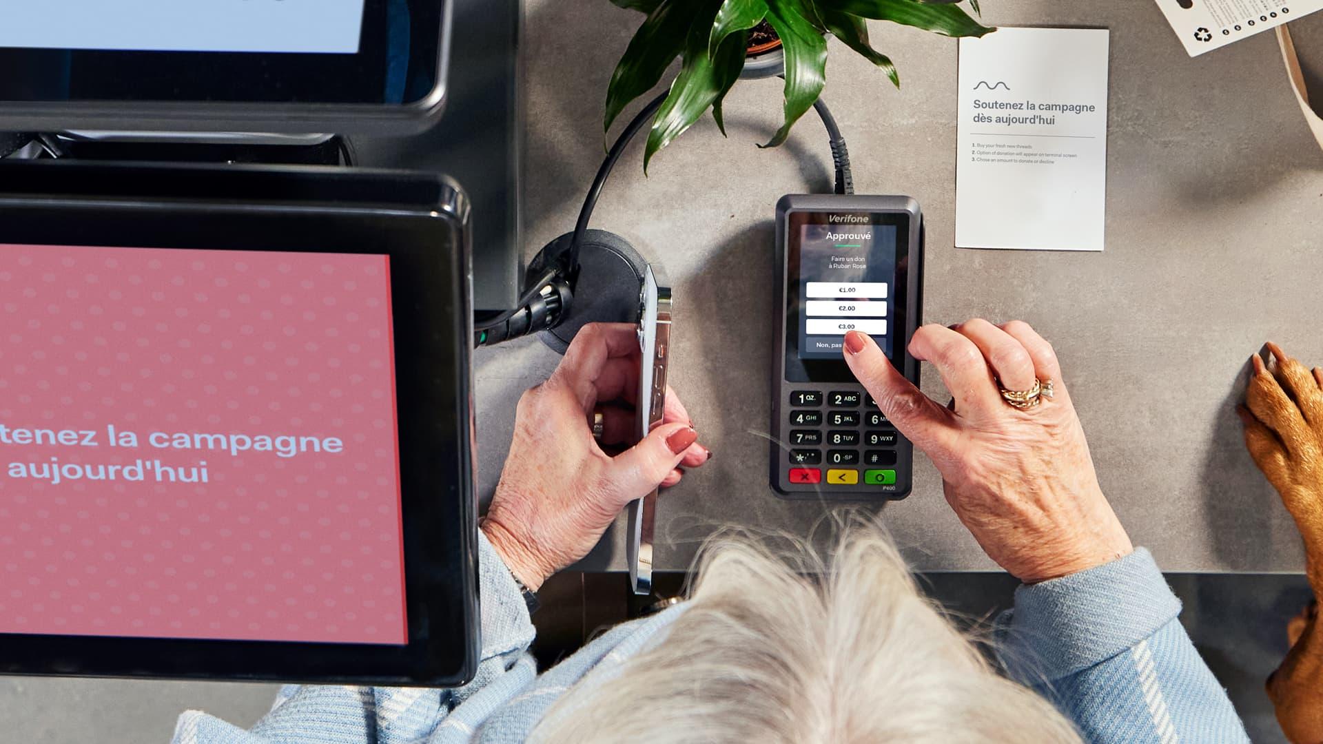 Personne utilisant un appareil de point de vente avec l'interface de paiement Adyen lors d'une transaction.