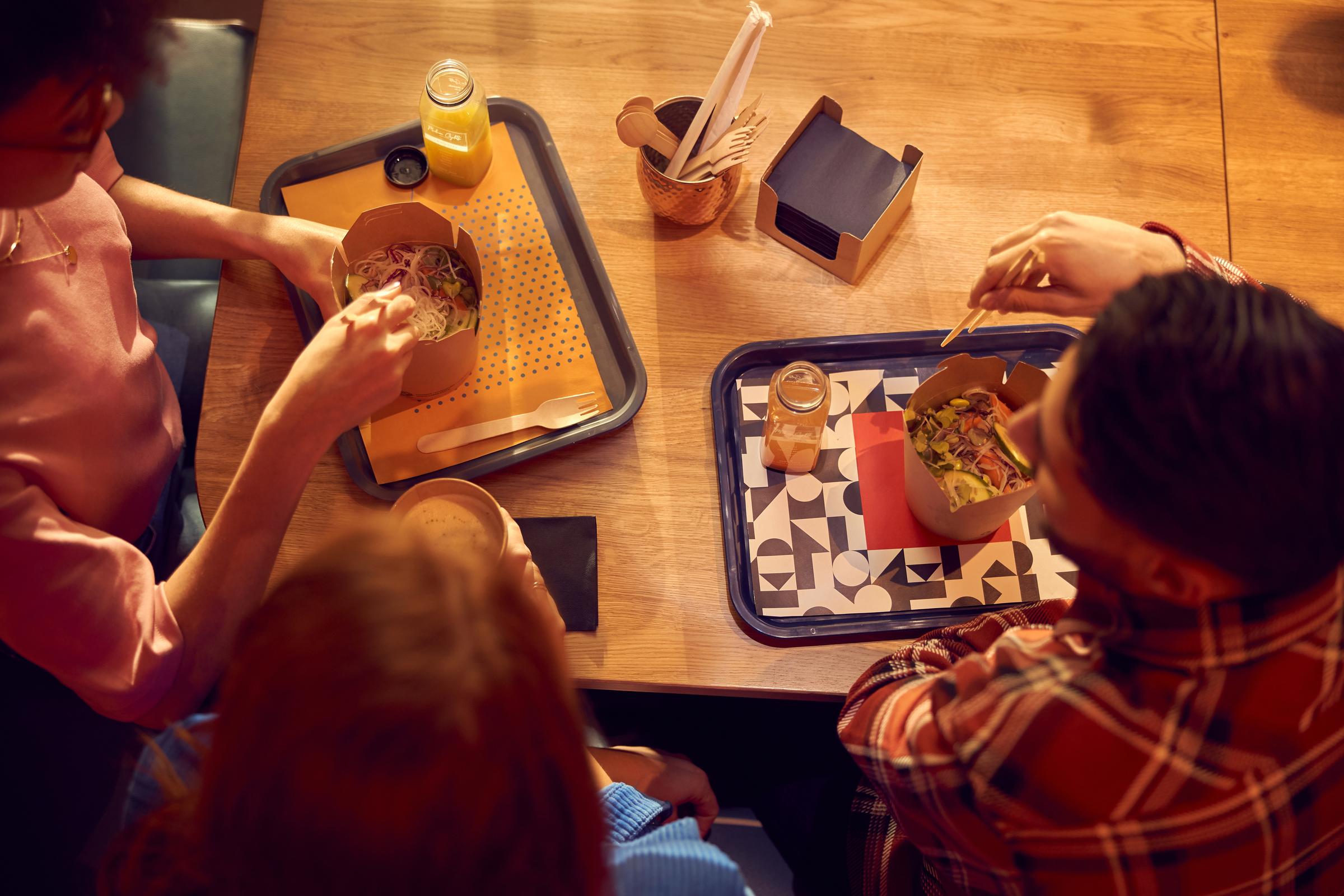People eating noodles in a quick service restaurant.