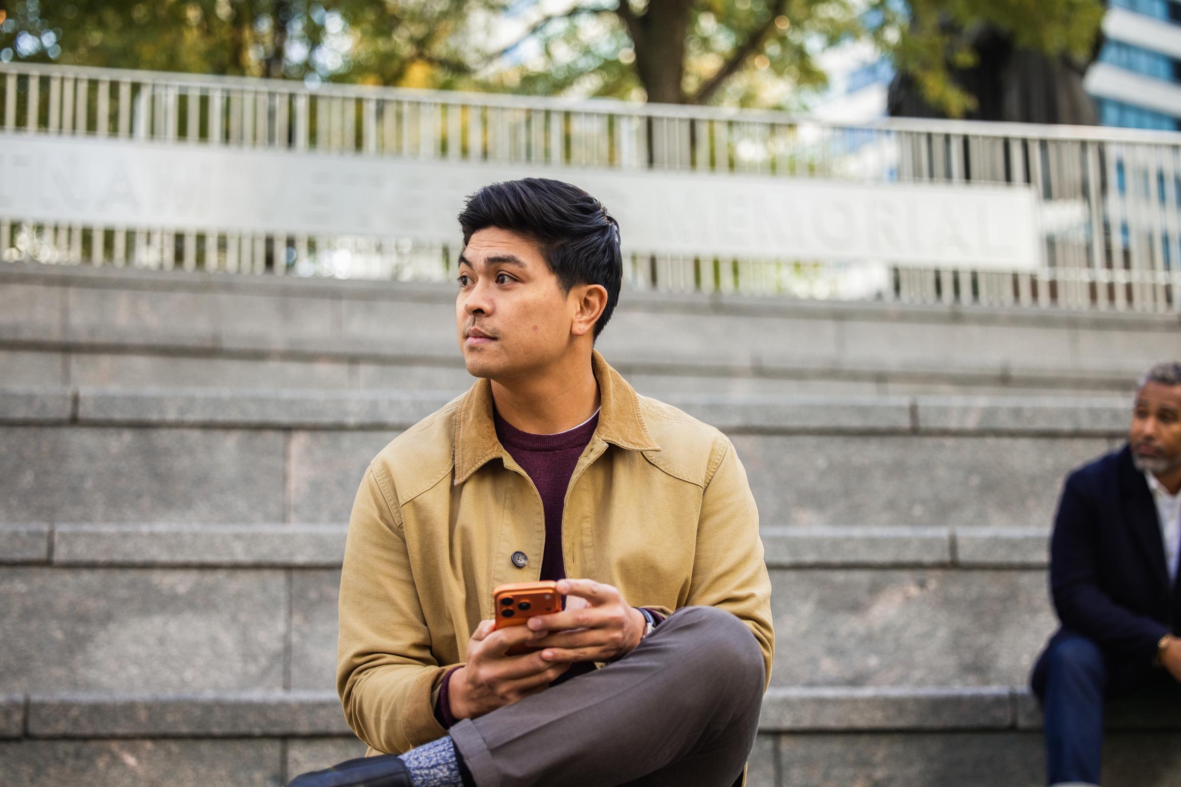 A person sitting outdoors using a mobile device, with payment processed via Adyen.